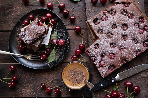 Delicious homemade  cherry, chocolate sheet cake. Served with dalgona coffee on rustic and wooden table background from above.