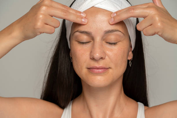 istock a young woman with closed eyes massaging her face 1589311758