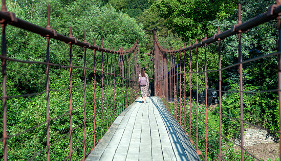 one young girl tourist walks on the bridge in thailand