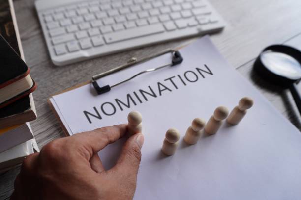 istock Hand pick wooden doll and text NOMINATION. 1589348402