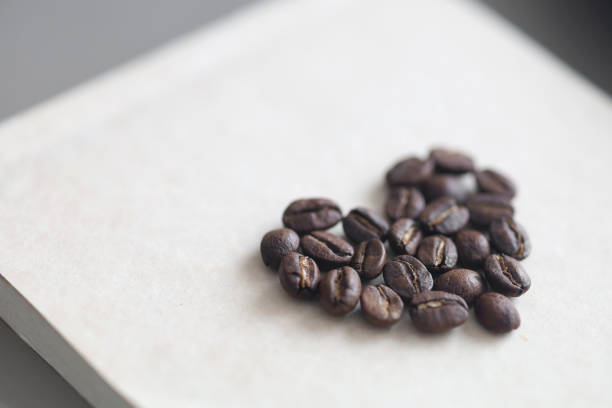 Heart shape coffee beans and full coffee cup inside it, directly above shot