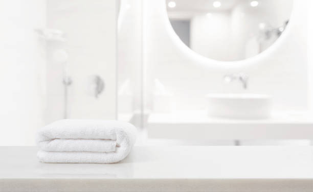 istock Fresh white spa towel on countertop in blurred moderm bathroom 1589379560