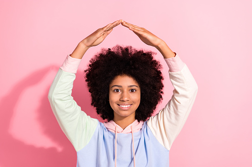Portrait of cute positive schoolkid beaming smile arms demonstrate roof above head gesture isolated on pink color background.