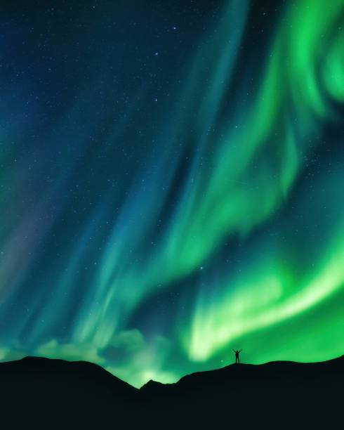 istock Aurora borealis glowing over hiker standing on mountain in arctic circle 1589402293