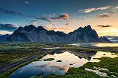 Sunrise over Vestrahorn mountain with wilderness and lake reflection in summer at Stokksnes peninsula