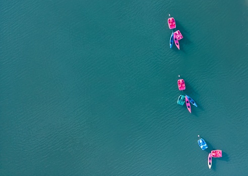 An aerial view of vibrant pedal boats, floating on the tranquil, crystal clear ocean