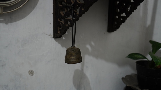 ancient doorbell made of dirty and corroded brass hanging by a string.