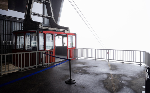 Wide view of an overhead cable car in Garmisch-Partenkirchen, Germany on a foggy morning. There is no one around.