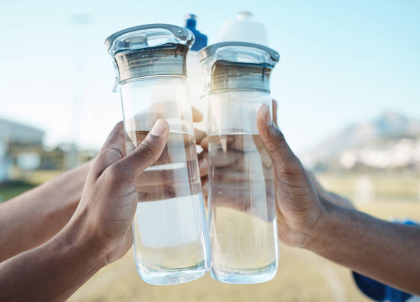 istock Fitness, water bottle or hands toast in stadium together after workout, exercise or training game outdoors. Sports target, cheers or closeup of team with liquid for hydration in celebration of goals 1589420104