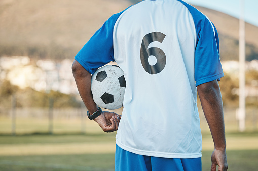 Soccer player shooting a ball on a field. About 30 years old, Caucasian male.