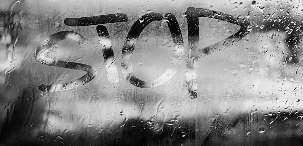 window with written finger word stop. concept photo. depression. rainy day