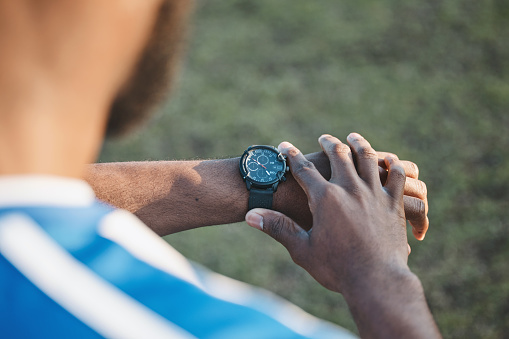 Hands, man or soccer player with smart watch on field to monitor time, training or exercise progress. Wellness, performance or healthy sports athlete with timer to check running workout or fitness