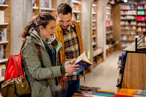 A young couple is spending a leisurely afternoon exploring the world of literature in a local book shop