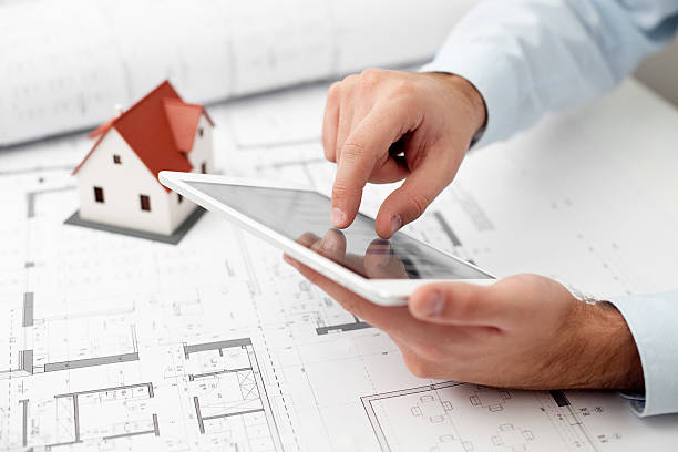 istock Architect zooming in on a tablet over a blueprint 158944485