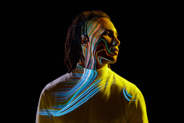 Handsome young african man with colorful neon stripes reflection on face posing against black background in neon light. Concept of art, fashion, modern style, cyberpunk, futurism, ad