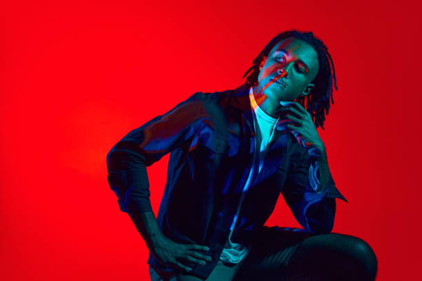 istock Young african man with neon filter reflection on face posing against red background in neon light. New vision 1589449606
