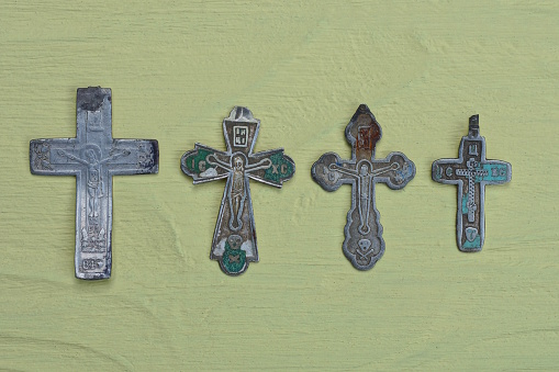 four small old gray silver crosses lie on a yellow table