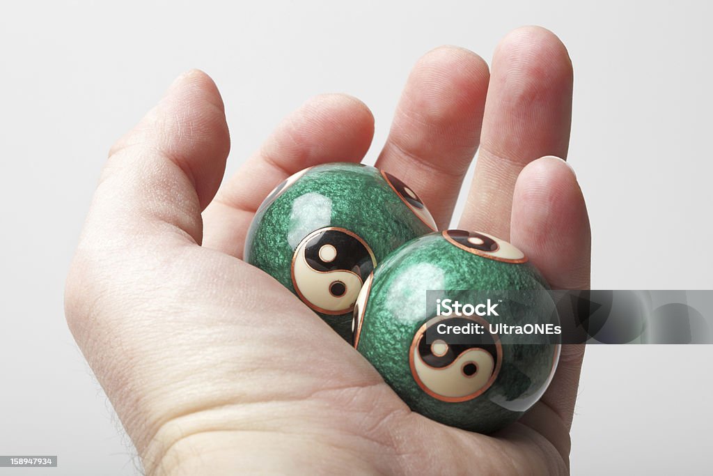 Man holding Yin Yang balls in hand Man holding Yin Yang balls in hand. Gray Background. Studio shot. Adult Stock Photo