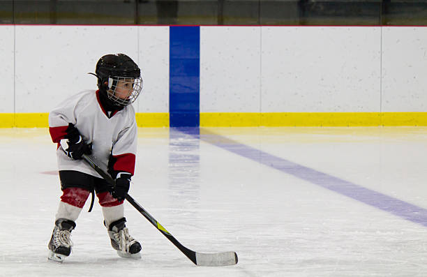 A little boy playing ice hockey on the rink stock photo