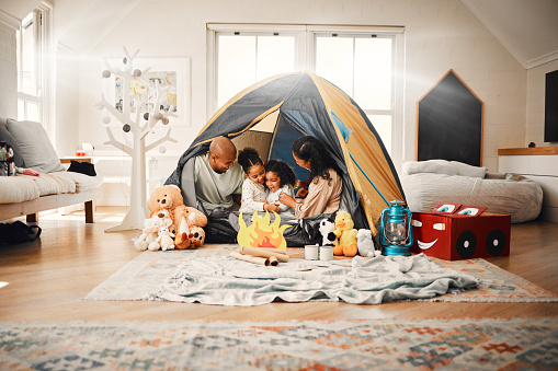 Love, home camping and happy family bonding, relax and enjoy time together having fun in living room. Happiness, youth and children playing with mother, father or parents in house adventure