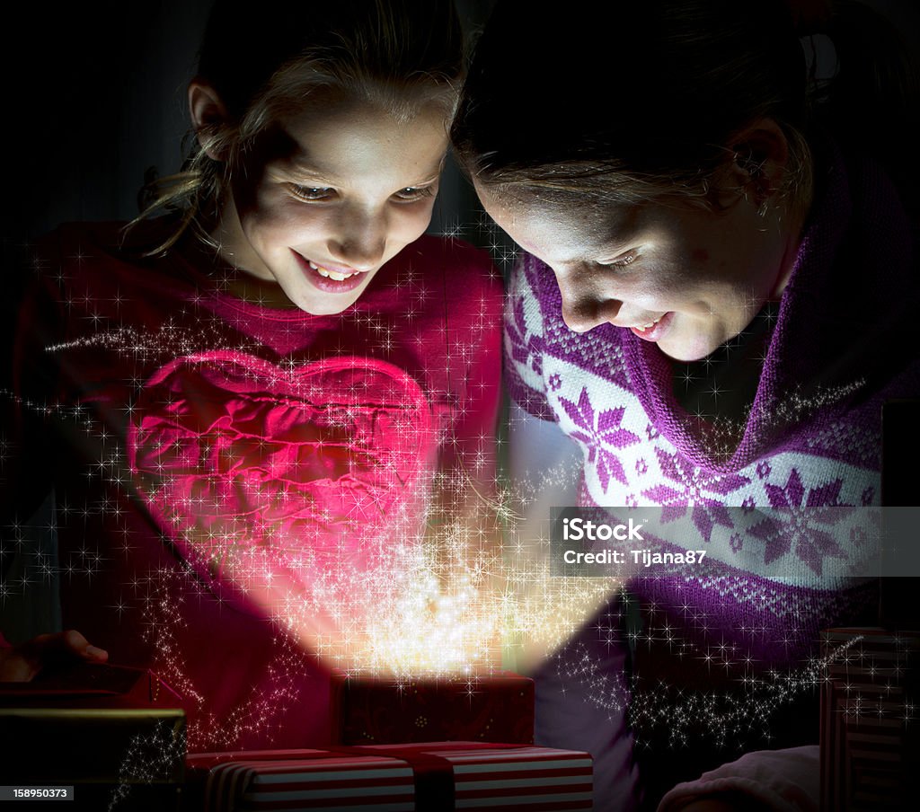 Two cute girls looking inside of a magical present Backgrounds Stock Photo