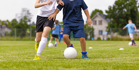 Legs of two young football players on a match. European football soccer youth player legs in action. Two soccer players running and kicking a soccer ball