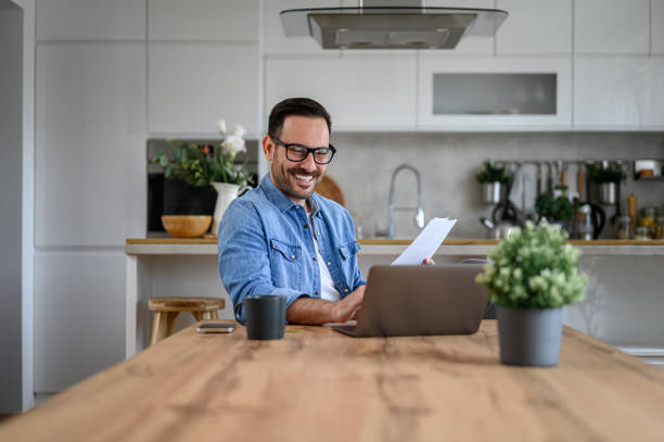 istock Smiling young financial adviser with report using laptop on desk while working from home office 1589525451