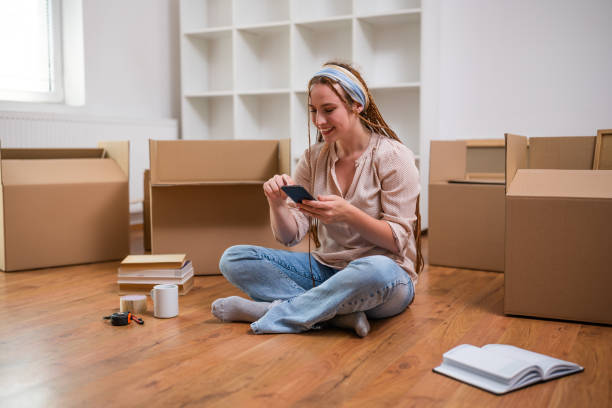istock Happy ginger woman using phone in her new home 1589542210