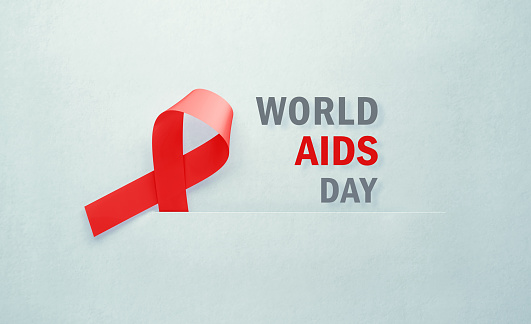 AIDS awareness ribbon sitting next to World AIDS Day message on gray background. Horizontal composition with copy space. World AIDS Day concept.