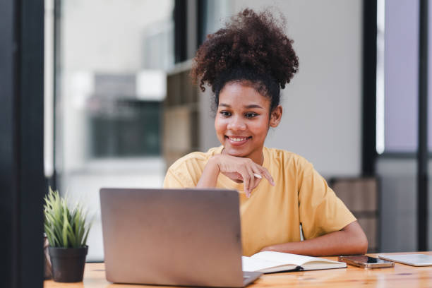 istock Young African American woman is taking notes in a notebook while watching a webinar video course. Afro american student listening to the lecture to study online through e-learning. 1589570258