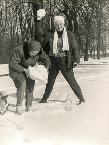 Vintage photo of mother and daughter fighting with snowballs, Poland, early sixties