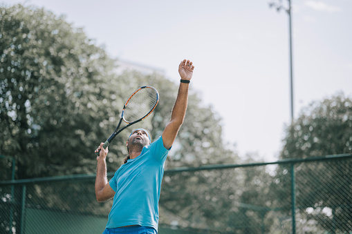 Asian male tennis player serving in tennis court