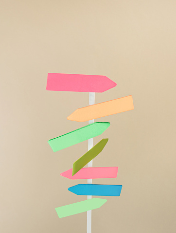 Funny direction multicolor signpost on beige background. Summer concept. Flat lay.