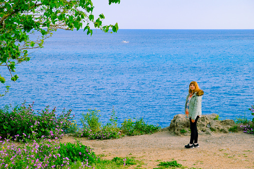 A woman watches the sea in the landscape where green and blue intertwine