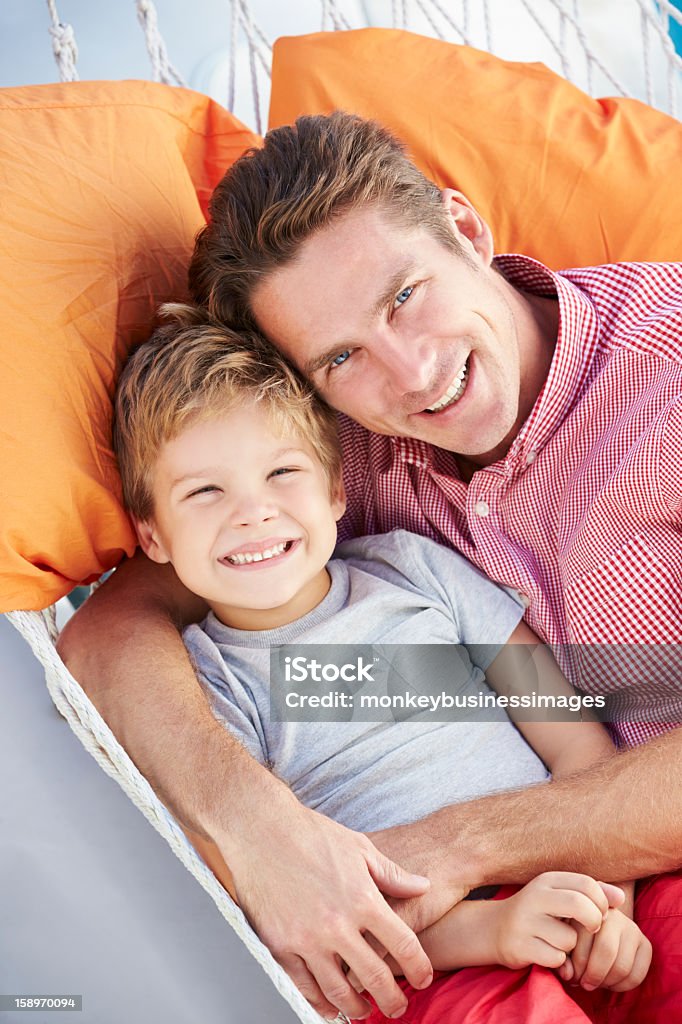 Padre e hijo de descansar en una hamaca junto al jardín - Foto de stock de Familia libre de derechos