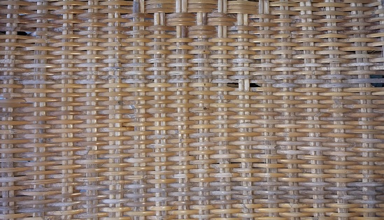 a photography of a woven wall with a hole in the middle, a close up of a woven basket with a black cat in it.