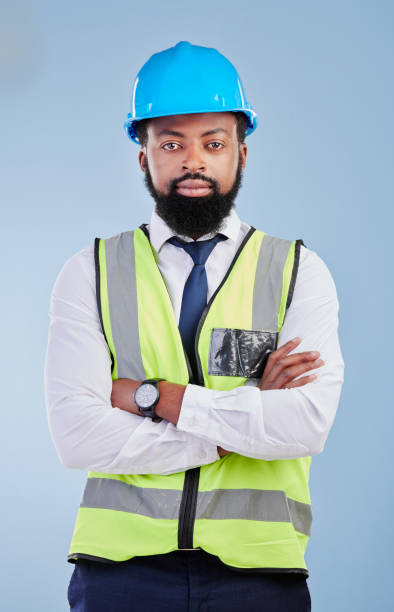 istock Engineering, man or serious portrait with arms crossed in studio in development, building construction or industrial technician. Black male architect, contractor or project manager on blue background 1589730653