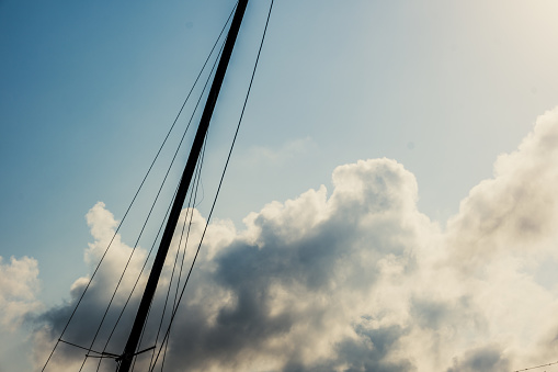 A boat mast with a cloudy sky in the background on the seaside