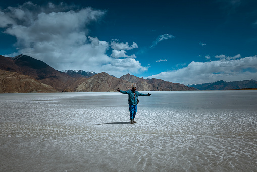 With Pangong Lake's icy surface as a backdrop, an Indian adult showcases pure happiness and a sense of adventure during their remarkable visit in late March 2023.