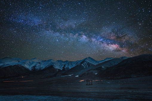 A Mesmerizing Night Landscape under the Bright Milky Way, snow-capped mountains are seen in the distance