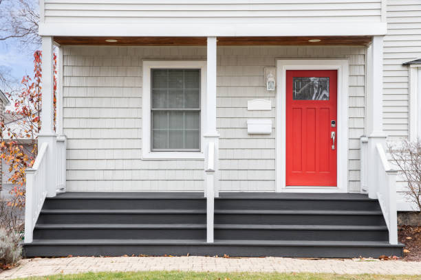 Detail of a home's front porch and red front door. Detail of a front porch of a white home with grey steps leading up to a red door. blue house red door stock pictures, royalty-free photos & images