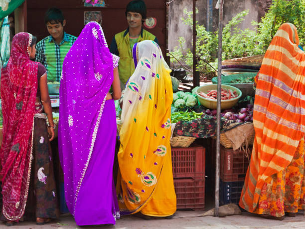 Colourful scene in an Indian street market Deorgah, India - March 8, 2015: Women in typically colourful Rajasthani dress buying fruit and vegetables in the crowded market area of the town tivoli bazaar stock pictures, royalty-free photos & images