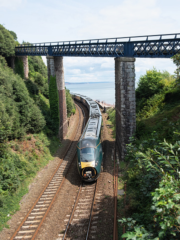 Devon, England – July 21, 2023: A Great Western Railway passenger service from London Paddington, part of their Hitachi class 800 series of trains, approaching Teignmouth station with a missing nose cone
