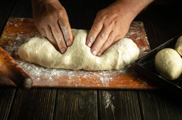 istock The baker's hands knead the dough before baking the buns. Work environment on the kitchen table in the bakery 1589826003