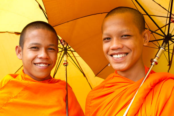 Bangkok, Thailand - Nov 01, 2023: three Buddhist monks in traditional orange robes exiting Wat Arun (the Temple of Dawn) via the back gate on a sunny morning