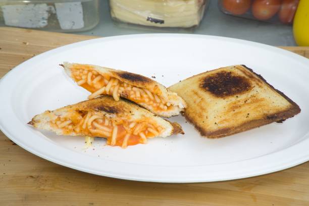 istock Spaghetti  toasted sandwich cooked using a Jaffle Iron over a campfire on an environmentally friendly disposable plate 1589837937