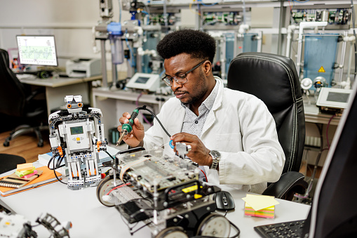 Mechatronics engineer works with soldering iron in laboratory