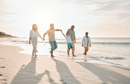 Holding hands, swing and big family at the beach walking with freedom, travel and bonding at sunset. Love, lifting and and boy child with grandparents and parents at sea on walk for summer holiday