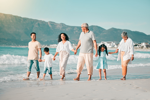 Generations holding hands, family is walking on beach and ocean waves, freedom and bonding in nature. Grandparents, parents and kids, people outdoor and travel with trust and love on Mexican holiday