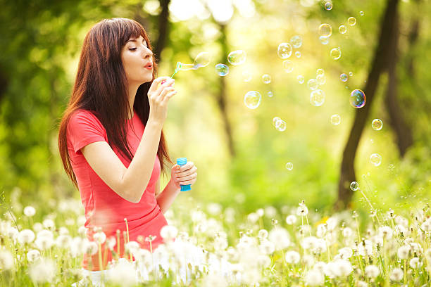 istock Happy woman blowing bubbles in the park 158987215